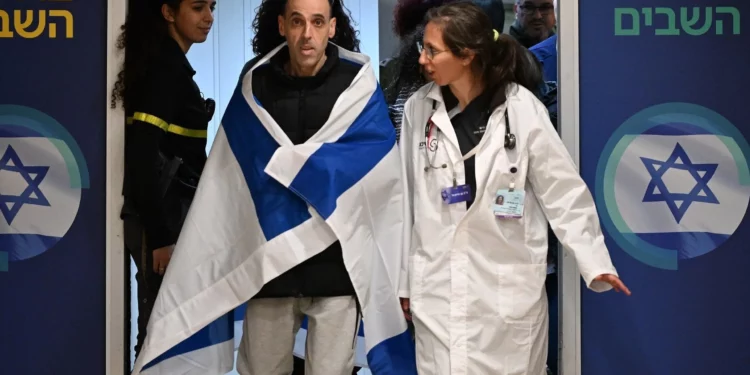 El rehén liberado Eli Sharabi llega al Centro Médico Sheba cerca de Tel Aviv, envuelto en una bandera israelí, mientras camina para reunirse con miembros de su familia después de 491 días de cautiverio en Hamás, el 8 de febrero de 2025. (Haim Tsach/GPO)