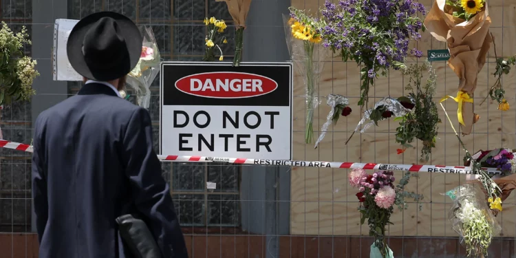 A member of the Jewish community reads messages attached to a fence where flowers have been left at the Adass Israel Synagogue in the Melbourne suburb of Ripponlea on December 9, 2024. (Martin Keep / AFP)