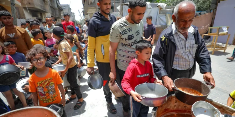 Palestinos reciben comidas de voluntarios en Deir al-Balah, en la Franja de Gaza, el 19 de abril de 2025. (Ali Hassan/Flash90)