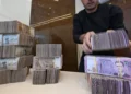 Un empleado de una casa de cambio apila billetes sirios en una tienda de Damasco el 16 de abril de 2025. (LOUAI BESHARA / AFP)