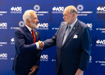 El embajador de Estados Unidos en Israel, Mike Huckabee (derecha), estrecha la mano del presidente de la región israelí del CJM, Sylvan Adams, en la inauguración de la asamblea plenaria del Congreso Judío Mundial en Jerusalén, el 18 de mayo de 2025. (Shauli Lendner)