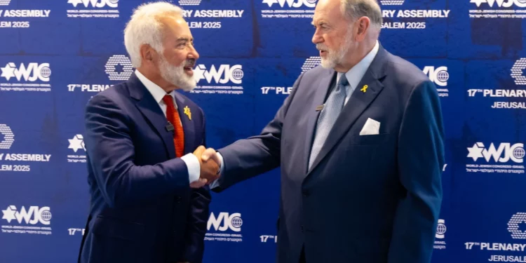 El embajador de Estados Unidos en Israel, Mike Huckabee (derecha), estrecha la mano del presidente de la región israelí del CJM, Sylvan Adams, en la inauguración de la asamblea plenaria del Congreso Judío Mundial en Jerusalén, el 18 de mayo de 2025. (Shauli Lendner)