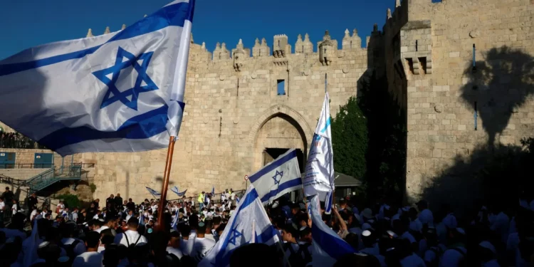 Activistas israelíes se reúnen con banderas nacionales israelíes frente a la Puerta de Damasco de la Ciudad Vieja de Jerusalén el 5 de junio de 2024, durante la marcha de las banderas del Día de Jerusalén. (Menahem Kahana / AFP)