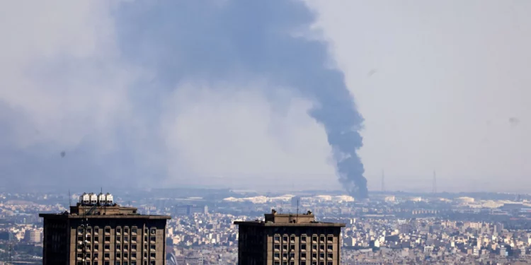 El humo se eleva a lo lejos desde una refinería de petróleo tras un ataque israelí contra la capital iraní, Teherán, el 17 de junio de 2025. (ATTA KENARE / AFP)