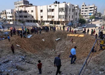 Palestinos se reúnen alrededor de un cráter causado por un ataque israelí contra un campamento de desplazados en la ciudad de Gaza, el 28 de junio de 2025. (AP/Jehad Alshrafi)