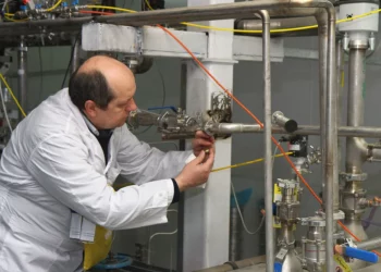 Un inspector no identificado del Organismo Internacional de Energía Atómica (OIEA) desconecta las conexiones entre las cascadas gemelas para la producción de uranio al 20% en el centro de investigación nuclear de Natanz, a unos 300 kilómetros al sur de Teherán, Irán, el 20 de enero de 2014. (KAZEM GHANE/IRNA/AFP)