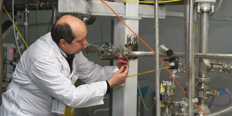 Un inspector no identificado del Organismo Internacional de Energía Atómica (OIEA) desconecta las conexiones entre las cascadas gemelas para la producción de uranio al 20% en el centro de investigación nuclear de Natanz, a unos 300 kilómetros al sur de Teherán, Irán, el 20 de enero de 2014. (KAZEM GHANE/IRNA/AFP)