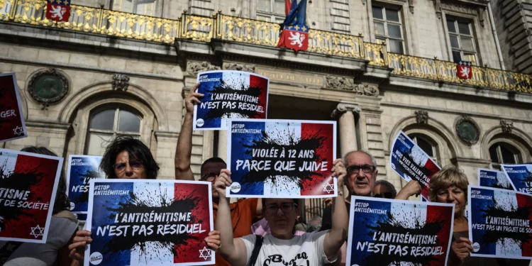 Manifestantes portan pancartas que dicen "El antisemitismo no es residual", "Más del 1000% en actos antisemitas, no son solo cifras", "Nuestras vidas valen más que el conflicto importado" y "Niña judía violada, la República en peligro", mientras se reúnen para condenar la presunta violación en grupo de una niña de 12 años por parte de un grupo antisemita, durante una manifestación en la plaza Lyon Terreaux de Lyon, en el centro-este de Francia, el 19 de junio de 2024. (Jean-Philippe Ksiazek/AFP)