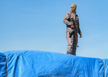 Un miembro de las fuerzas de seguridad leales a Hamás monta guardia encima de un camión que transporta ayuda humanitaria procedente del cruce de Kerem Shalom, cerca de la ciudad de Rafah, en el extremo sur de Gaza, el 21 de enero de 2025. (Bashar Taleb/AFP)