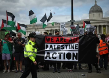 Agentes de policía vigilan a manifestantes con pancartas durante una protesta en apoyo del grupo antiisraelí y propalestino Palestine Action, en Trafalgar Square, en el centro de Londres, el 23 de junio de 2025. (HENRY NICHOLLS / AFP)