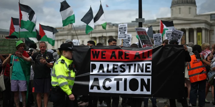 Agentes de policía vigilan a manifestantes con pancartas durante una protesta en apoyo del grupo antiisraelí y propalestino Palestine Action, en Trafalgar Square, en el centro de Londres, el 23 de junio de 2025. (HENRY NICHOLLS / AFP)