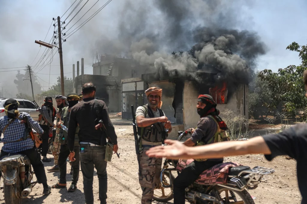 Combatientes beduinos se congregaron frente a una tienda incendiada en la localidad de Mazraa, en las afueras de Sweida, Siria, el 18 de julio de 2025. (AP/Ghaith Alsayed) 