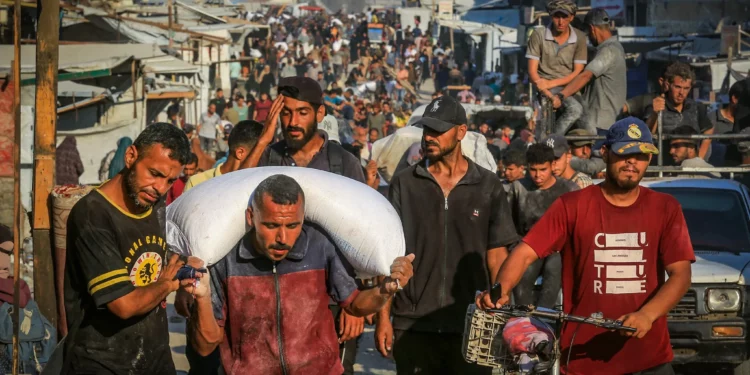 Gazatíes caminan por las calles con sacos de harina después de que los camiones de ayuda humanitaria llegaran a través del cruce de Kerem Shalom controlado por Israel hacia el sur de Gaza, en Jan Yunis, el 24 de julio de 2025. (Abed Rahim Khatib/Flash90)