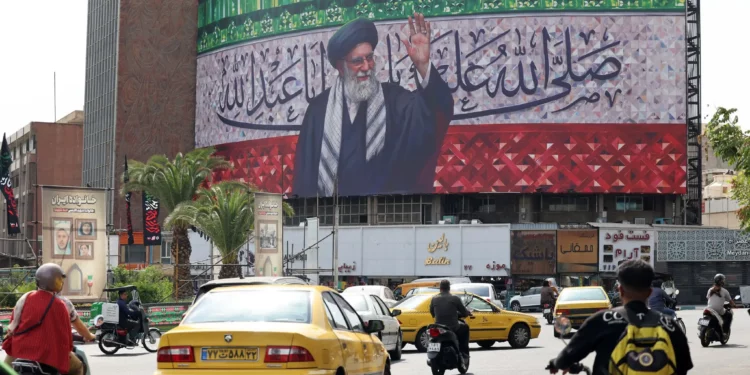 Los conductores pasan junto a una valla publicitaria que representa al líder supremo de Irán, el ayatolá Alí Jamenei, en el centro de la plaza Valiasr de Teherán, el 13 de julio de 2025. (ATTA KENARE / AFP)