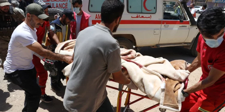 Voluntarios de la Media Luna Roja transportan a un soldado del gobierno herido en la ciudad de Sweida durante los enfrentamientos entre las fuerzas gubernamentales y las milicias drusas en una clínica en la aldea de Busra al-Harir, en el sur de Siria, el martes 15 de julio de 2025. (Foto AP/Omar Albam)