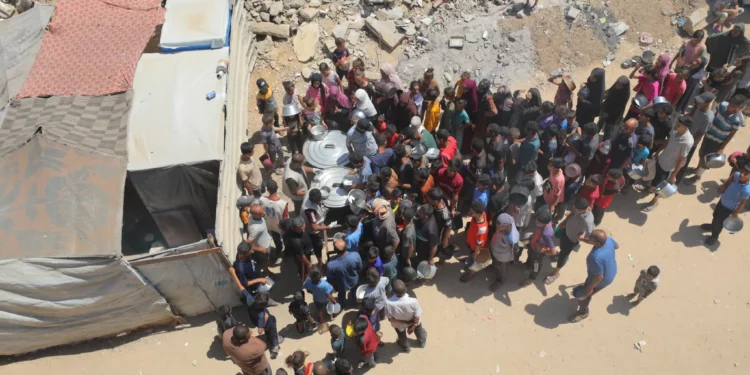Palestinos reciben comidas de voluntarios en Deir al-Balah, en el centro de la Franja de Gaza, el 14 de julio de 2025. (Ali Hassan/Flash90)