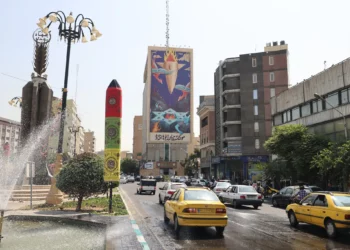 El tráfico fluye junto a una enorme valla publicitaria con la imagen de un misil cayendo sobre Israel y el lema en farsi: “El misil ha caído entre los demonios”, en una avenida principal del centro de Teherán, el 16 de julio de 2025. (Foto de ATTA KENARE / AFP)