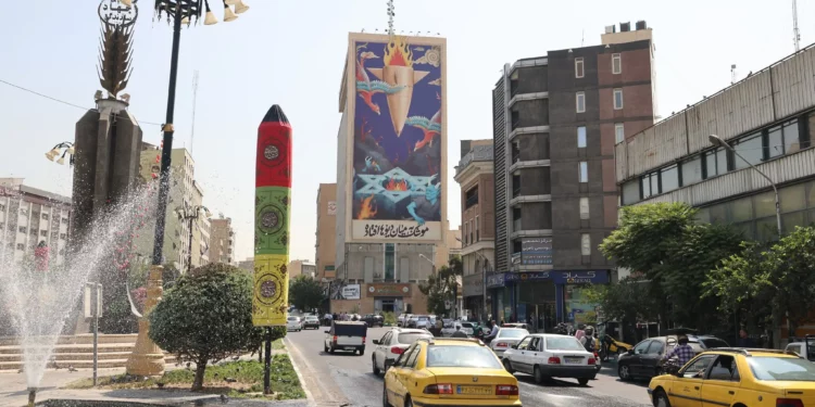 El tráfico fluye junto a una enorme valla publicitaria con la imagen de un misil cayendo sobre Israel y el lema en farsi: “El misil ha caído entre los demonios”, en una avenida principal del centro de Teherán, el 16 de julio de 2025. (Foto de ATTA KENARE / AFP)