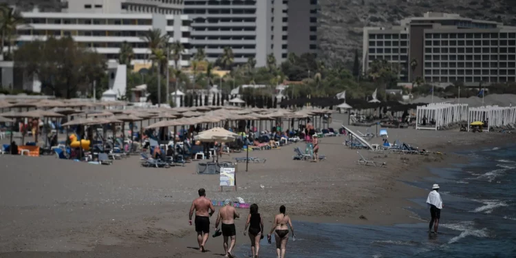Turistas caminan por la playa frente a los hoteles en la isla egea de Rodas el 29 de agosto de 2020. (Louisa GOULIAMAKI / AFP)