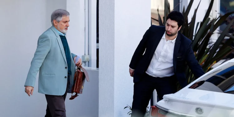 El embajador iraní en Australia, Ahmad Sadeghi (izq.), camina hacia su automóvil dentro de los terrenos de la embajada de la República Islámica de Irán en Canberra el 27 de agosto de 2025 (Hilary Wardhaugh / AFP)