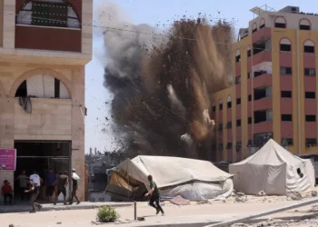 Gzatíes corren a resguardarse mientras el humo se eleva después de un ataque israelí contra un edificio en Yabalia, en el norte de la Franja de Gaza, el 20 de agosto de 2025. (BASHAR TALEB / AFP)