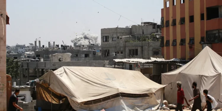 Gazatíes observan cómo el humo se eleva después de un ataque israelí contra un edificio en Yabalia, en el norte de la Franja de Gaza, el 20 de agosto de 2025. (BASHAR TALEB / AFP)