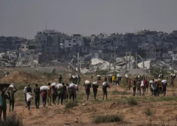 Gsazatíes llevan paquetes de ayuda humanitaria cerca de un centro de distribución de la Fundación Humanitaria de Gaza operado por la organización respaldada por Estados Unidos, en Netzarim, en el centro de la Franja de Gaza, el 4 de agosto de 2025. (AP Foto/Abdel Kareem Hana)