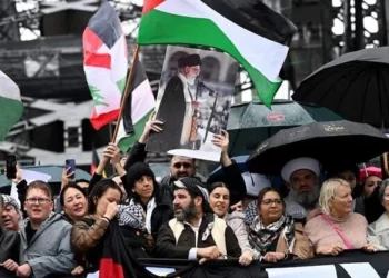 Un manifestante levanta un retrato del líder supremo de Irán, el ayatolá Ali Jamenei, al otro lado del puente del puerto de Sídney durante una manifestación propalestina y antiisraelí en Sídney el 3 de agosto de 2025. (Foto de Saeed KHAN / AFP)