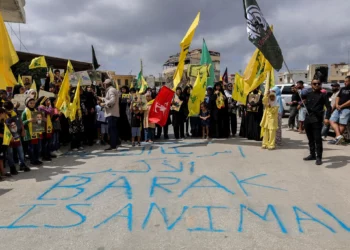 Manifestantes ondean banderas de Hezbolá tras una pintada que dice “Barak es un animal” mientras protestan contra la visita prevista del enviado estadounidense Tom Barrack al sur del Líbano, el 27 de agosto de 2025, en Khiam. (Rabih DAHER / AFP)