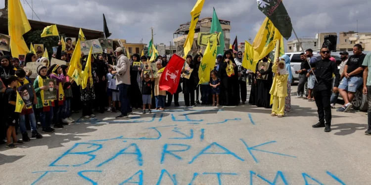 Manifestantes ondean banderas de Hezbolá tras una pintada que dice “Barak es un animal” mientras protestan contra la visita prevista del enviado estadounidense Tom Barrack al sur del Líbano, el 27 de agosto de 2025, en Khiam. (Rabih DAHER / AFP)