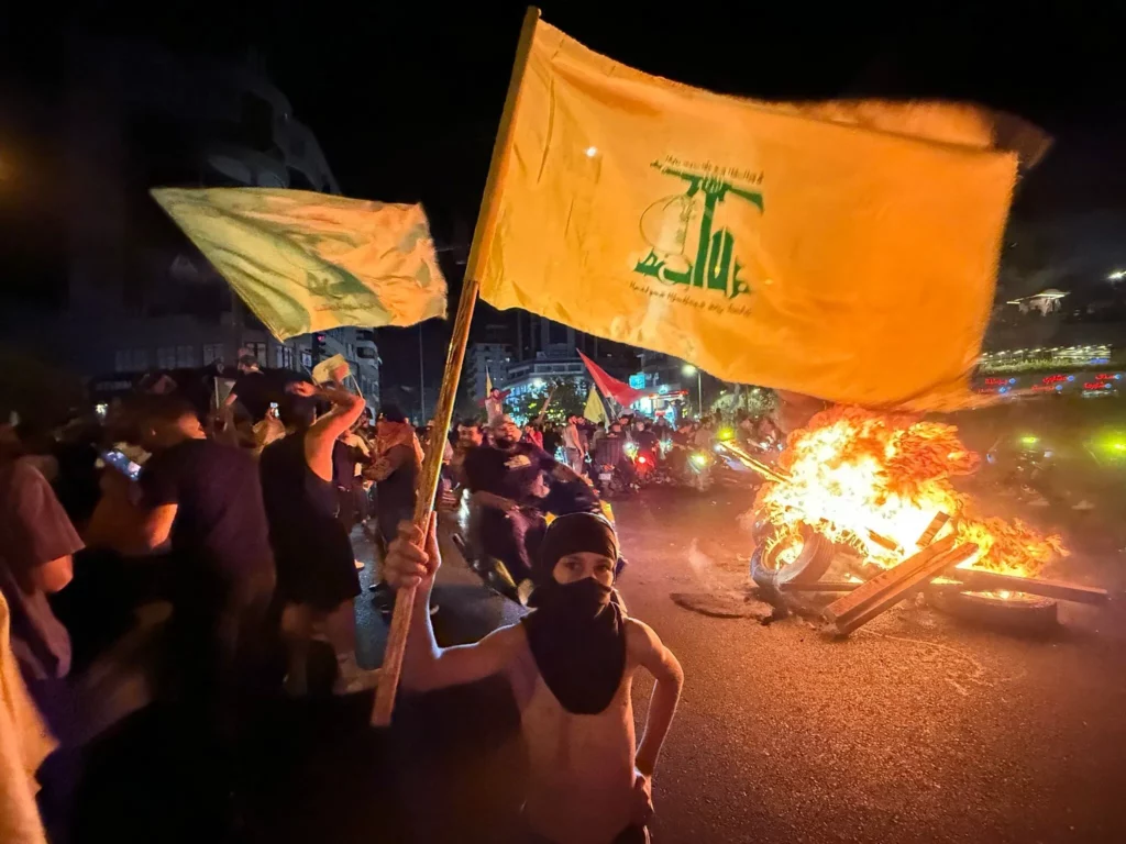 Los partidarios del grupo terrorista libanés Hezbolá bloquean las calles con neumáticos en llamas mientras se reúnen en automóviles y motocicletas para protestar por el respaldo del gobierno a un plan para desarmarlo, en los suburbios del sur de Beirut, la madrugada del 8 de agosto de 2025. (Ibrahim AMRO / AFP) 