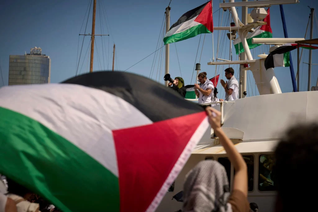 Manifestantes gritan consignas en un barco antes del lanzamiento de una flotilla civil con destino a Gaza, con el objetivo de romper el bloqueo israelí y entregar ayuda humanitaria en Barcelona, España, el 31 de agosto de 2025. (AP/Emilio Morenatti) 