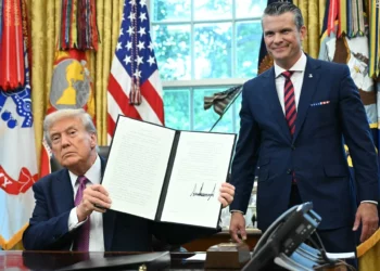 El presidente de Estados Unidos, Donald Trump, muestra una orden ejecutiva firmada mientras el secretario de Defensa, Pete Hegseth, observa en la Oficina Oval de la Casa Blanca en Washington, el 5 de septiembre de 2025. (Mandel Ngan/AFP)