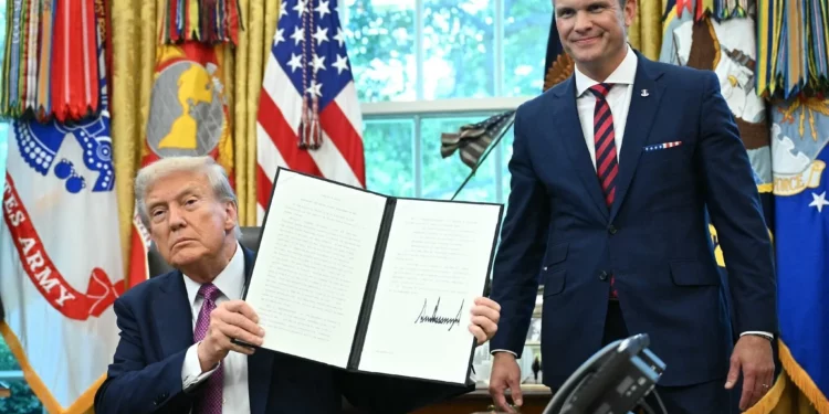El presidente de Estados Unidos, Donald Trump, muestra una orden ejecutiva firmada mientras el secretario de Defensa, Pete Hegseth, observa en la Oficina Oval de la Casa Blanca en Washington, el 5 de septiembre de 2025. (Mandel Ngan/AFP)