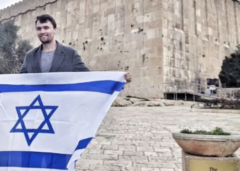 Charlie Kirk sostiene una bandera israelí fuera de la Tumba de los Patriarcas en Hebrón, Judea y Samaria, en una imagen sin fecha (Itamar Ben Gvir/X vía JTA)