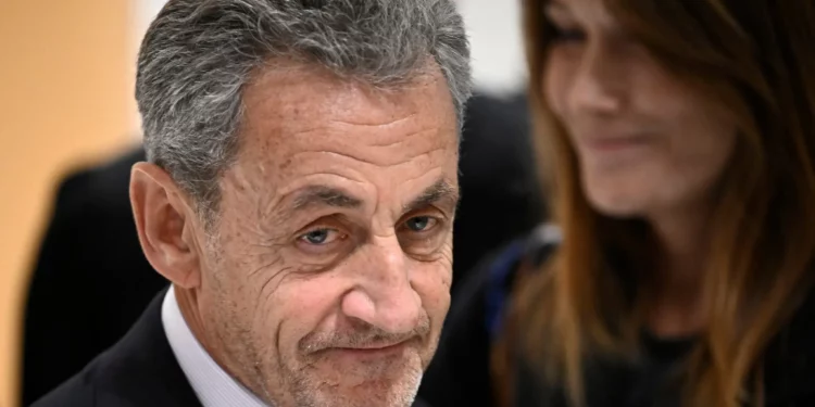 El expresidente francés Nicolas Sarkozy se va junto a su esposa, la cantante franco-italiana Carla Bruni, después del veredicto en su juicio por financiación ilegal de la campaña de Libia para su exitosa candidatura presidencial de 2007, en el Tribunal de París en París, el 25 de septiembre de 2025. (JULIEN DE ROSA / AFP)