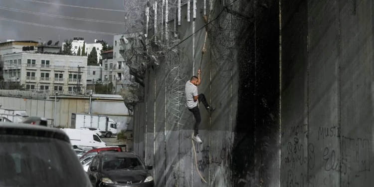 Imagen ilustrativa: Un palestino sube la barrera de seguridad en la ciudad de Al-Ram para cruzar ilegalmente a Israel, el 15 de septiembre de 2024. (AP/ Mahmoud Illean)