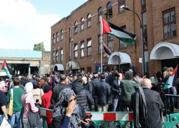 Personas asisten a una ceremonia de izamiento de la bandera palestina frente a la Misión Palestina en el Reino Unido, en el oeste de Londres, el 22 de septiembre de 2025. (Foto de Adrian DENNIS / AFP)