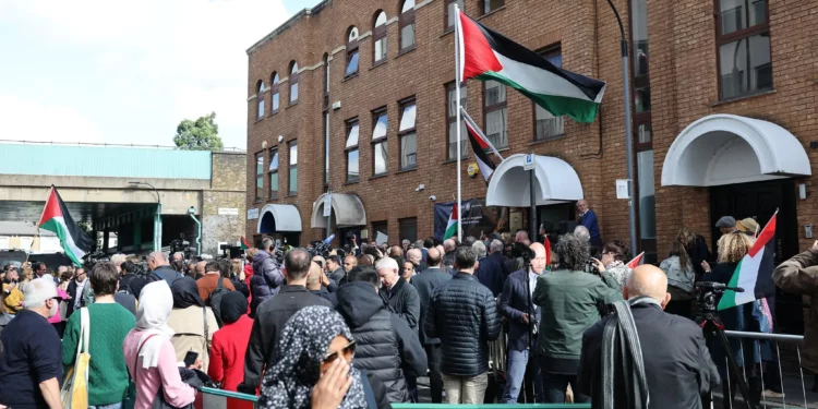 Personas asisten a una ceremonia de izamiento de la bandera palestina frente a la Misión Palestina en el Reino Unido, en el oeste de Londres, el 22 de septiembre de 2025. (Foto de Adrian DENNIS / AFP)