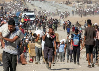 La gente camina con bolsas de ayuda humanitaria que recibieron en un centro de distribución administrado por la Fundación Humanitaria de Gaza (GHF), respaldada por Estados Unidos e Israel, mientras cruzan el corredor de Netzarim en el centro de la Franja de Gaza, el 22 de agosto de 2025. (Eyad BABA / AFP)