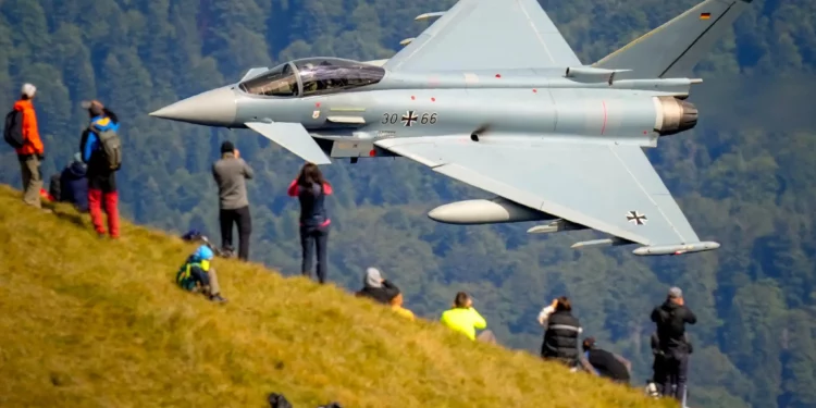 Aficionados de la aviación observan el sobrevuelo de un avión Eurofighter Typhoon de la Fuerza Aérea Alemana durante una exhibición de aviación militar y acrobática cerca de la Cruz de los Héroes en el pico Caraiman, en la cima de las montañas Bucegi, en Busteni, Rumania, el 26 de agosto de 2025. (Foto AP/ Vadim Ghirda)