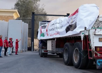 Miembros de la Media Luna Roja Egipcia vigilan los camiones con ayuda humanitaria a su entrada al cruce de Rafah, entre Egipto y la Franja de Gaza, tras el acuerdo de alto el fuego entre Israel y Hamás, el 12 de octubre de 2025. (AP/Mohamed Arafat)