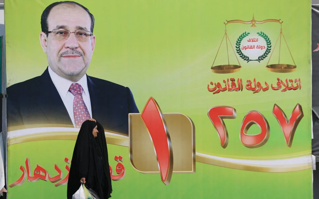 Una mujer pasa junto a una valla publicitaria electoral con un retrato del ex primer ministro iraquí Nuri al-Maliki en el centro de Bagdad, Irak, el 19 de octubre de 2025. (Ahmad Al-Rubaye / AFP)