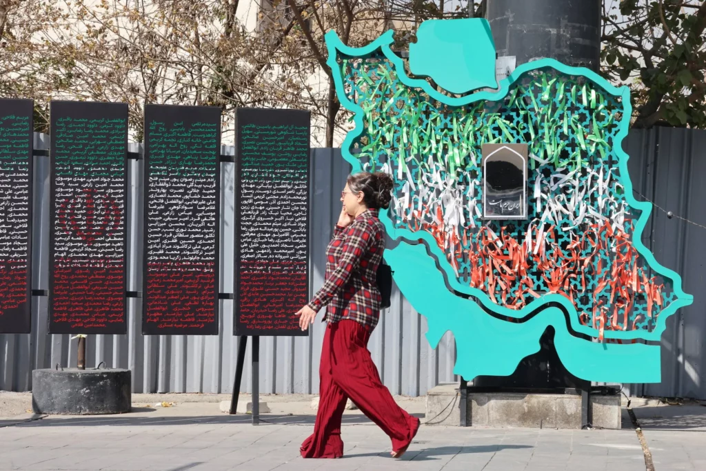 Una mujer iraní pasa junto a un mapa de Irán en Teherán el 13 de octubre de 2025. (ATTA KENARE / AFP) 