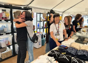 Dana Felz-Russo, a la izquierda, y otros voluntarios que venden mercancías en la Plaza de los Rehenes de Tel Aviv celebran un acuerdo para traer de vuelta a los 48 cautivos restantes el 9 de octubre de 2025 (Ben Sales/Times of Israel)