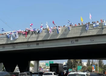 Multitudes se congregan en el puente Aluf Sade sobre la autopista 4 en dirección a Petah Tikvah, a la espera del cortejo fúnebre de Inbar Haiman, vestida de rosa en honor a su apodo, Pink, el 1 de octubre de 2025. (Yael Gadot/Movimiento de Protesta Prodemocrática de Israel)