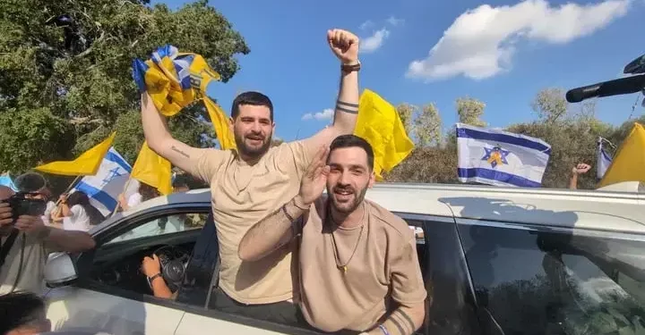 Los rehenes liberados Gal y Ziv Berman saludan a la multitud extasiada que les da la bienvenida al kibutz Beit Guvrin el 19 de octubre de 2025 (Tanya Zion-Waldoks/Movimiento de Protesta Prodemocracia Israelí)