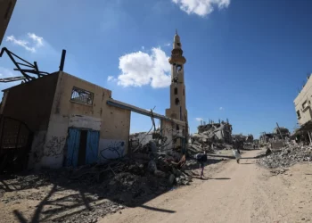 Palestinos caminan junto a edificios destruidos mientras los residentes desplazados regresan a sus hogares en la zona de Al-Zahra, al norte del campo de refugiados de Nuseirat, en el centro de la Franja de Gaza, el 14 de octubre de 2025. (Eyad BABA / AFP)