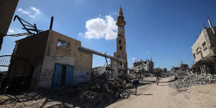 Palestinos caminan junto a edificios destruidos mientras los residentes desplazados regresan a sus hogares en la zona de Al-Zahra, al norte del campo de refugiados de Nuseirat, en el centro de la Franja de Gaza, el 14 de octubre de 2025. (Eyad BABA / AFP)