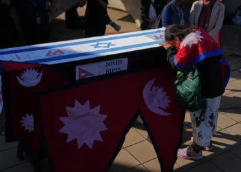 Familiares y amigos del ciudadano nepalí Bipin Joshi, quien fue tomado como rehén por Hamás en Gaza, junto a su ataúd durante una ceremonia de despedida antes de que su cuerpo sea trasladado a Nepal para su entierro en el Aeropuerto Ben Gurion, el 19 de octubre de 2025. (AP/Ariel Schalit)